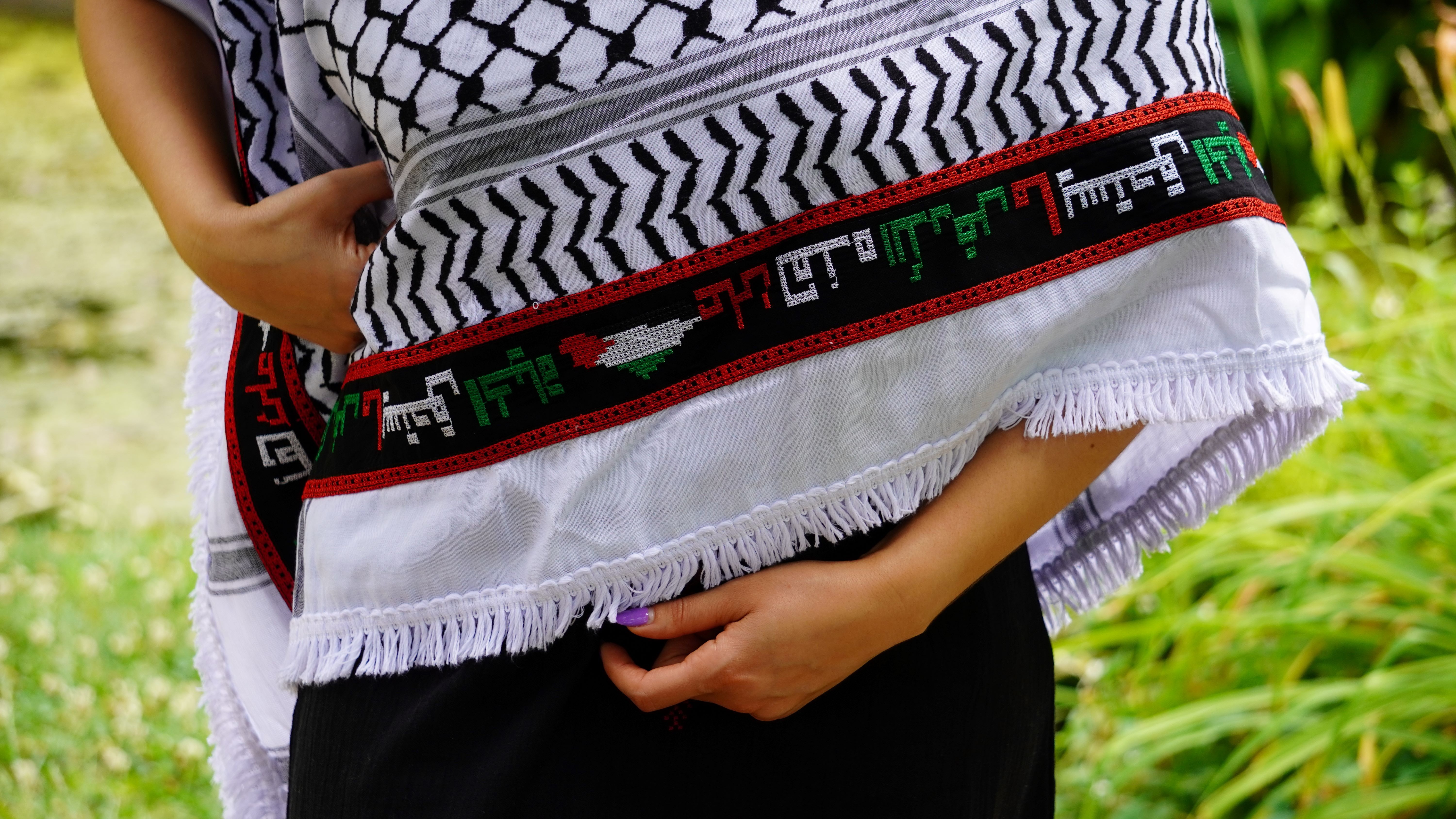 Keffieh blanc et noir brodé rouge avec la phrase arabe « علَى هَذِهِ الأَرْض مَا يَسْتَحِقُّ الحَياةْ ».