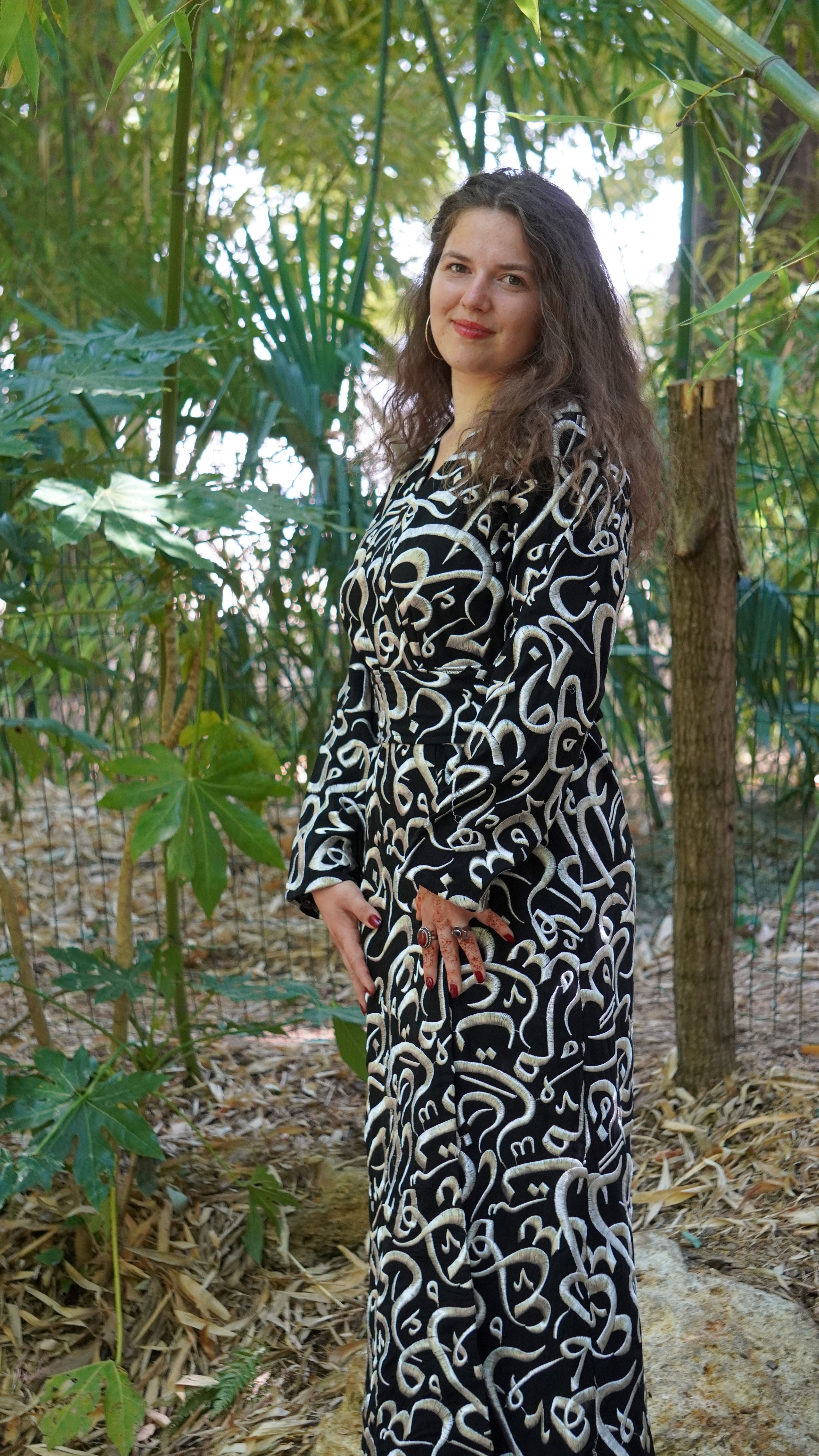 Femme portant un haut blanc brodé et une longue jupe noire brodée.
