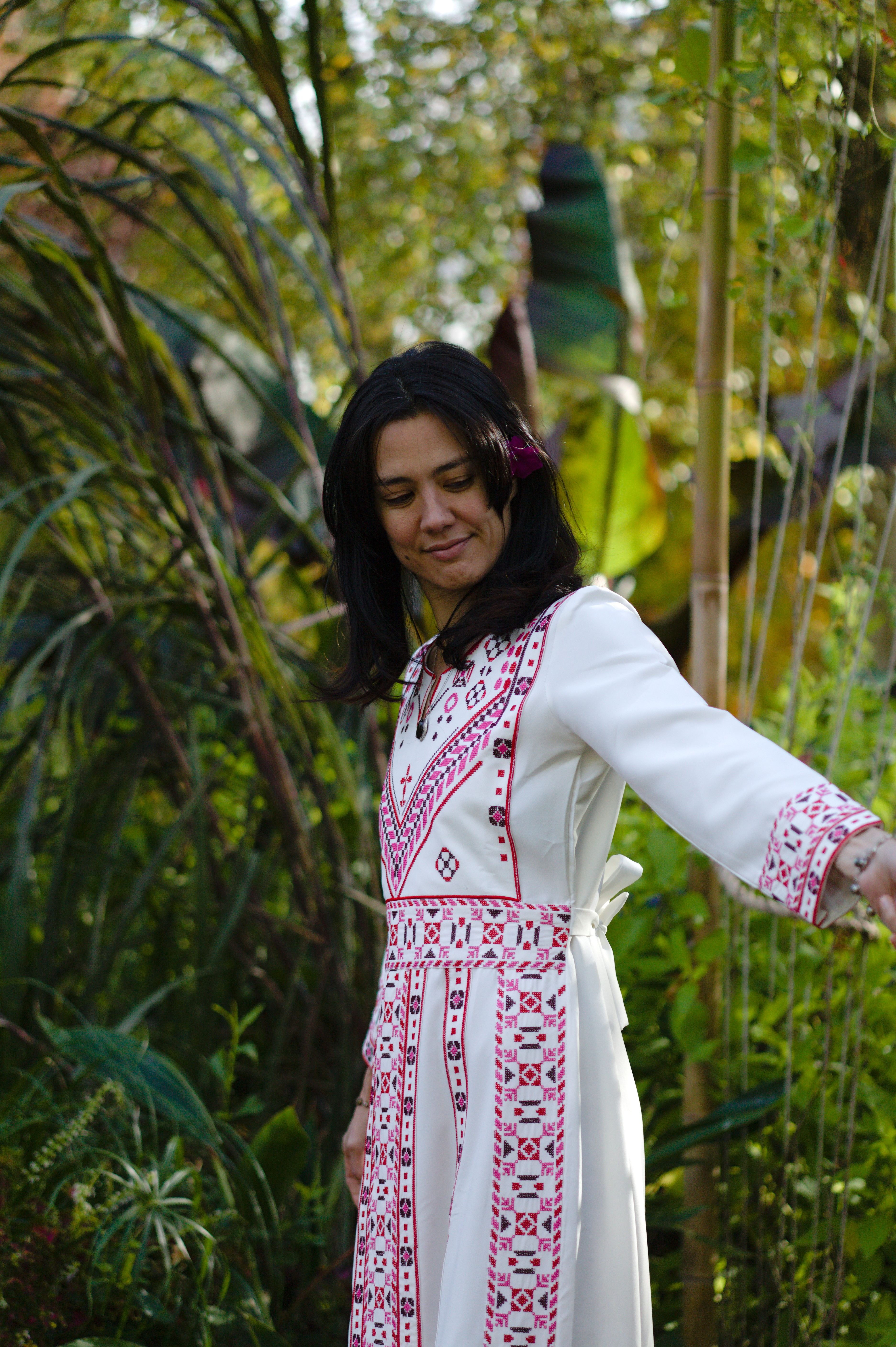 Femme portant une robe noire richement brodée de motifs multicolores.